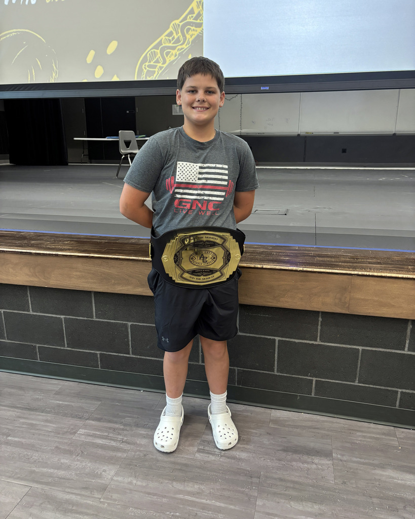 Student Ambassador with WIN THE MOMENT large belt on smiling for the camera in front of stage