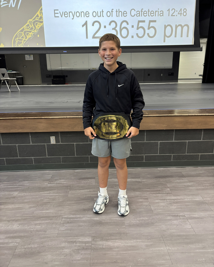 student holding belt in front of the stage after winning "Win the Moment" 