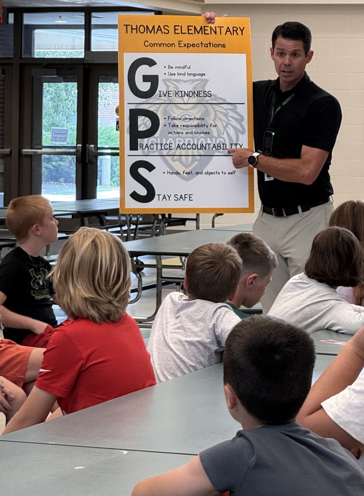 Mr. Basye the principal holding the expectations poster and reviewing expectations with 5th grade students.