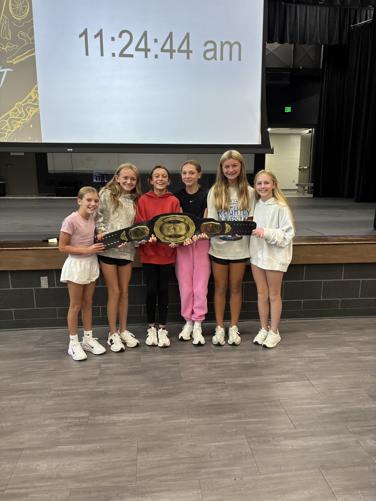six students standing in front of stage with "Win the Moment" belt 