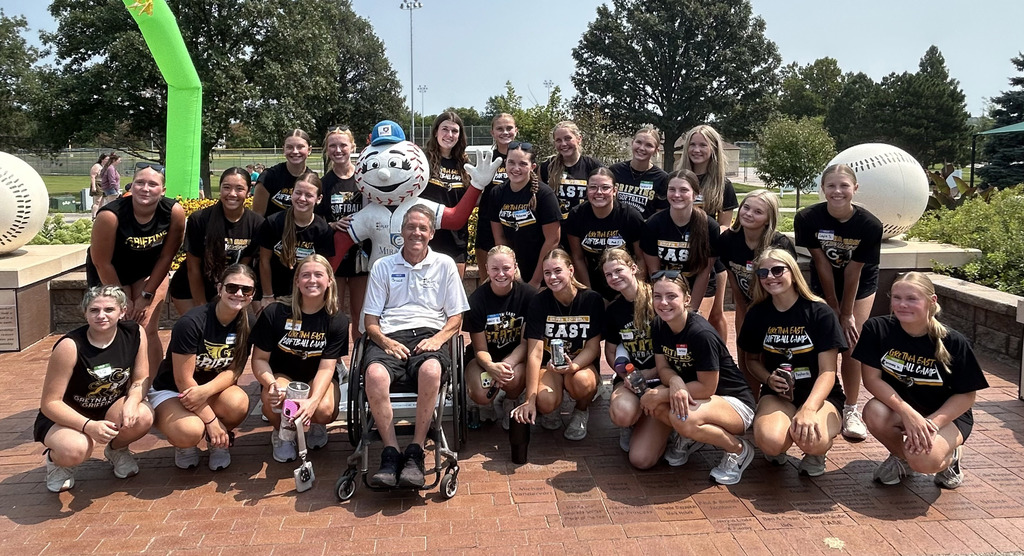 large group of Gretna East High School softball players and ALLPLAY mascot posing for group photo outside