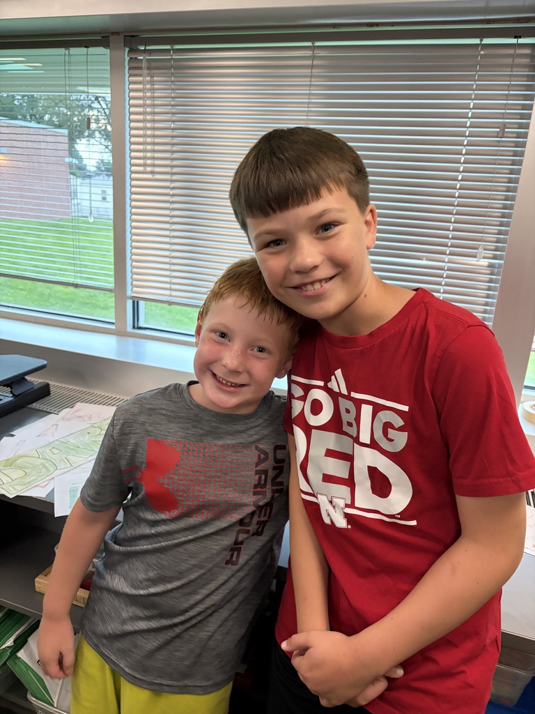 Two young boys leaning head-to-head, one in a grey shirt and the other in a red "Go Big Red" shirt.