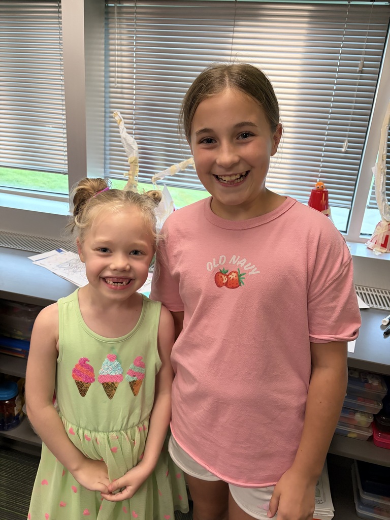 Two young girls smiling, one in a light green ice cream cone dress and the other in a pink Old Navy shirt.