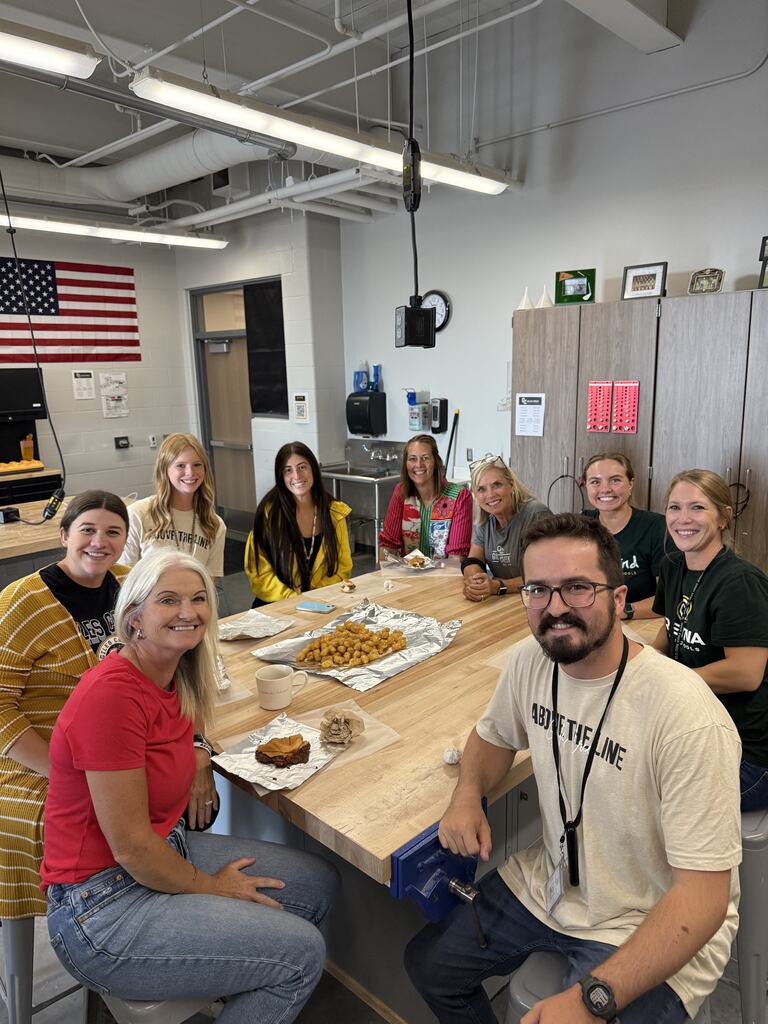 Teachers gathered around a table eating lunch.