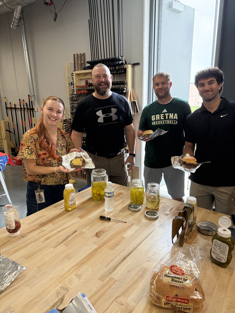 Four teachers smiling holding hamburgers.
