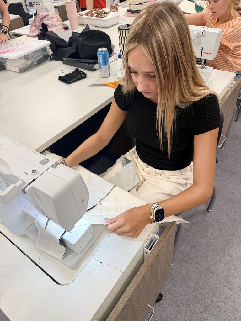 Student sewing at a sewing machine.