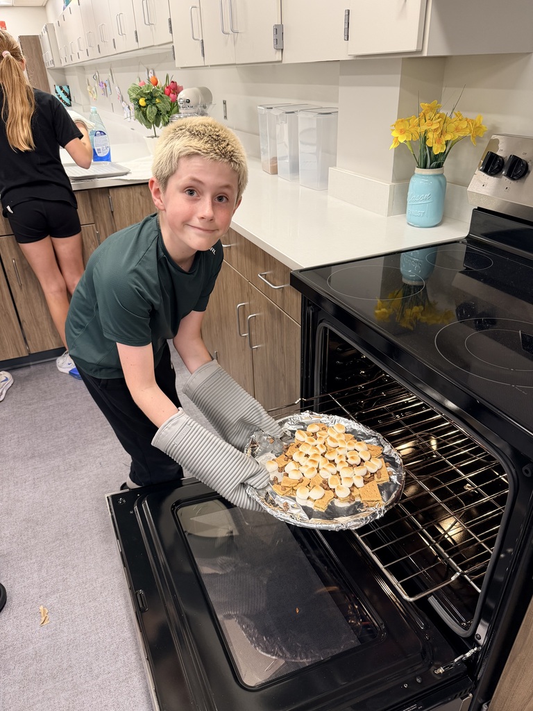 A student pulling food out of the oven.