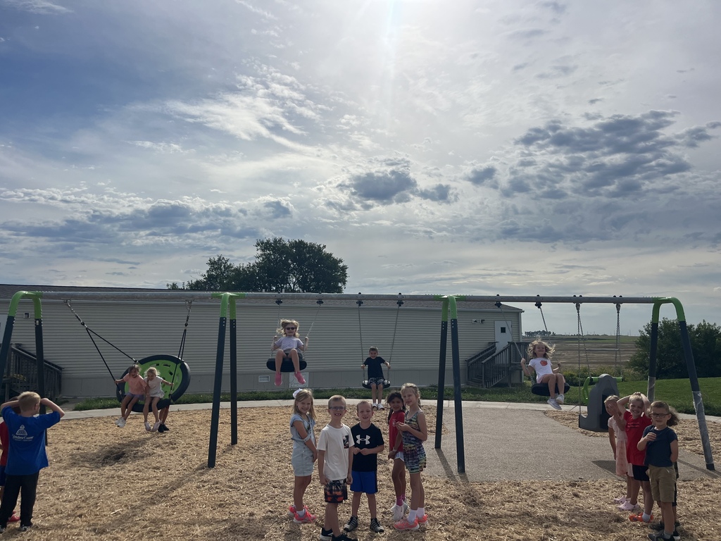 First grade students outside swinging on swings and waiting in line