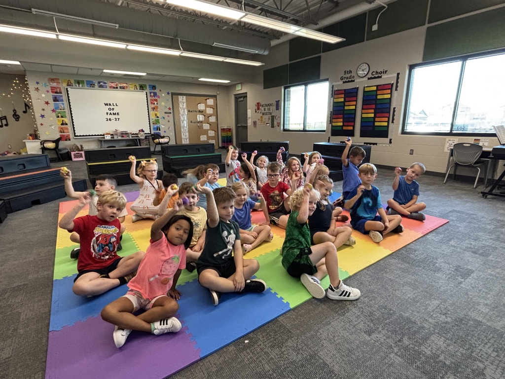 students practicing with instruments in music class sitting on the floor with egg shakers