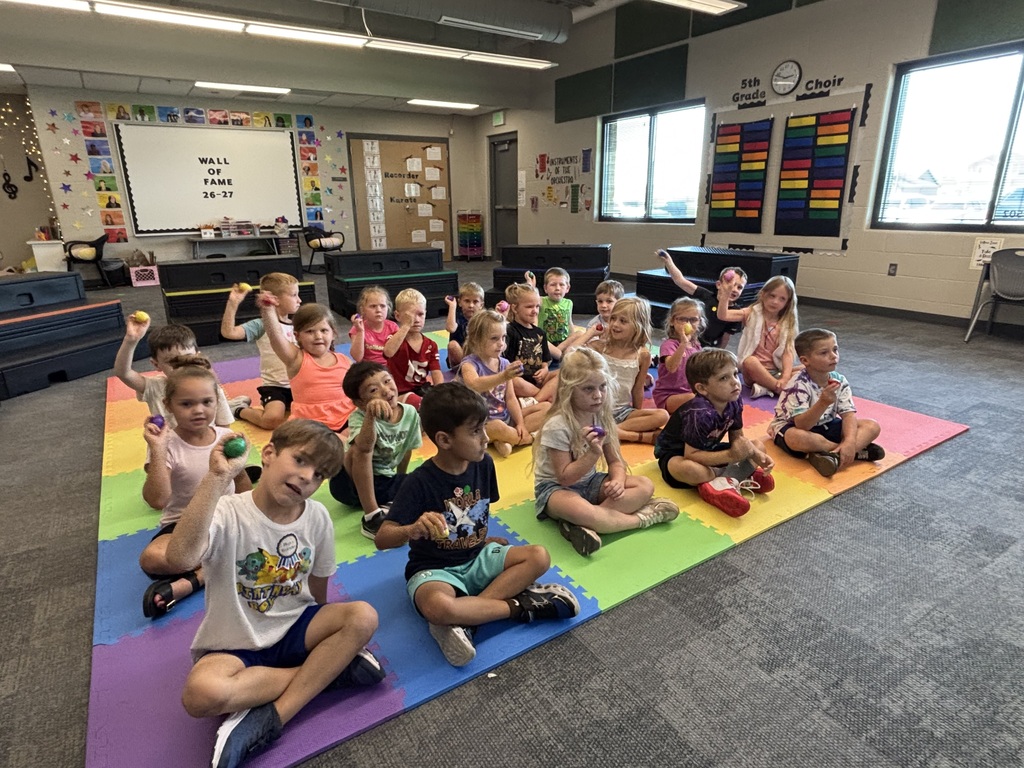 students practicing with instruments in music class sitting on the floor with egg shakers