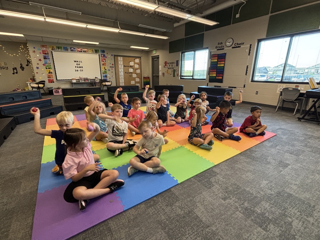 students practicing with instruments in music class sitting on the floor with egg shakers