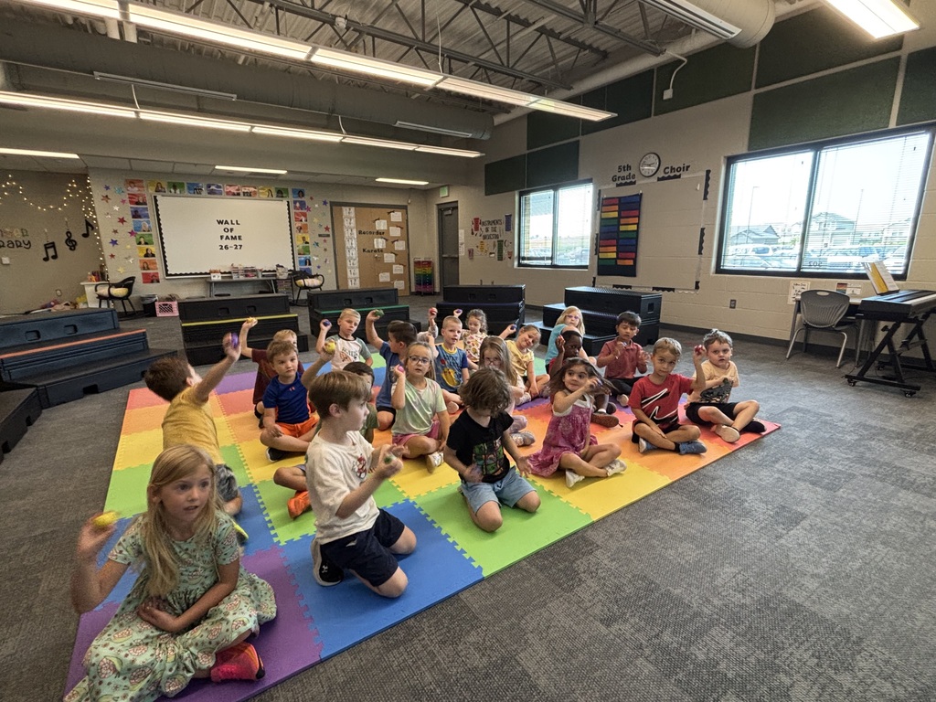 students practicing with instruments in music class sitting on the floor with egg shakers