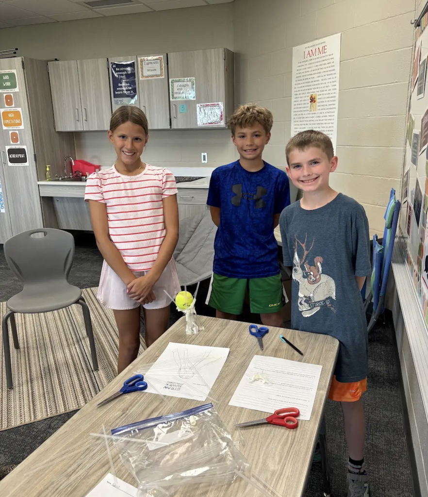 students smiling during the middle of their stem project