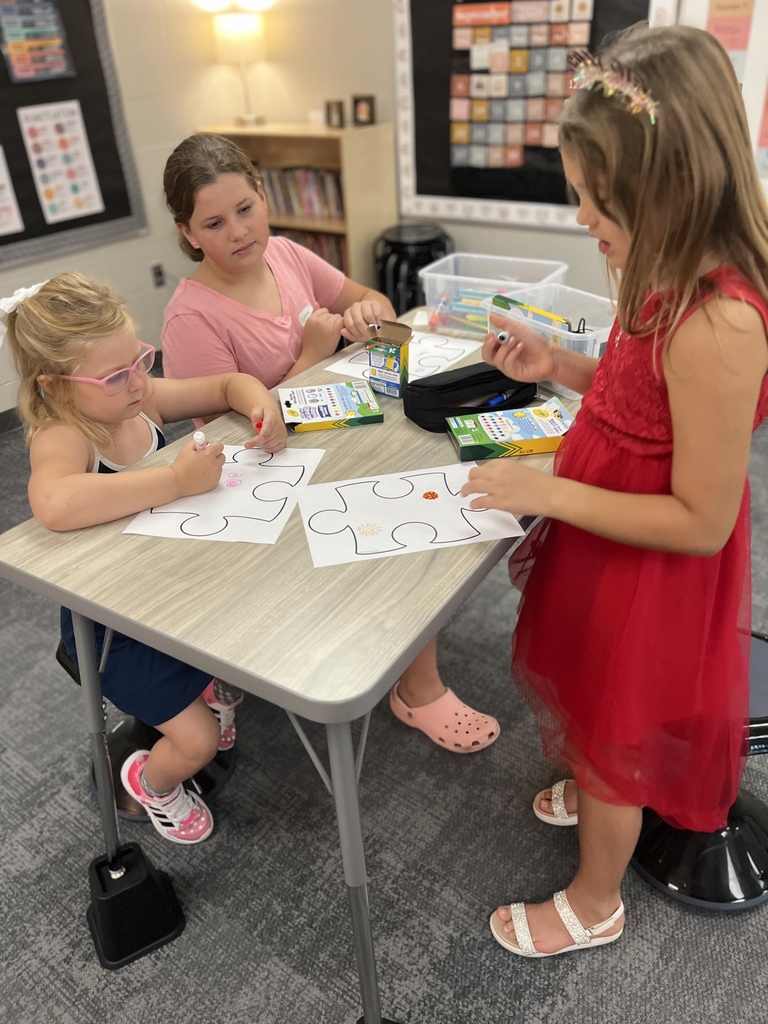 students working on a puzzle piece coloring project at a table in the classroom