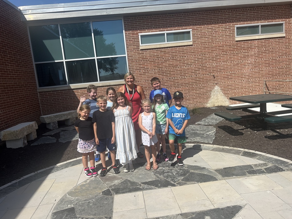 Group of students and a teacher standing outside in an outdoor classroom