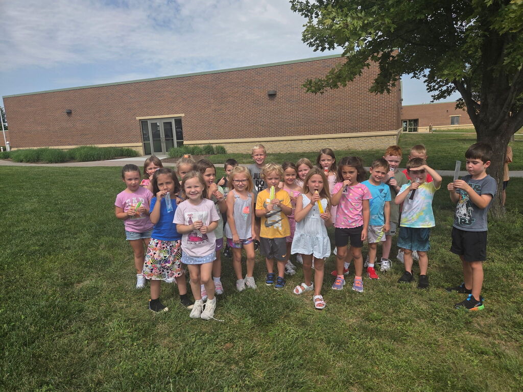 Students are standing outside eating popsicles.