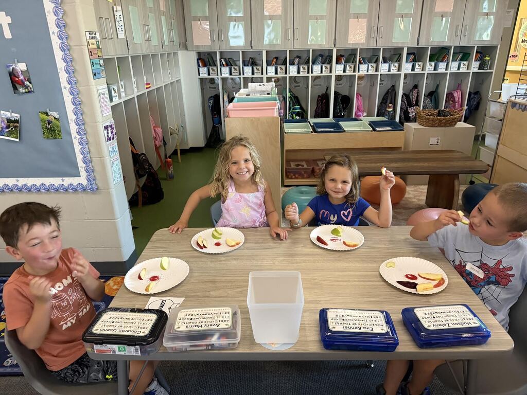 kindergarten students taste testing apples in a kindergarten classroom at harvest hills. They have multiple types of apples on their plate
