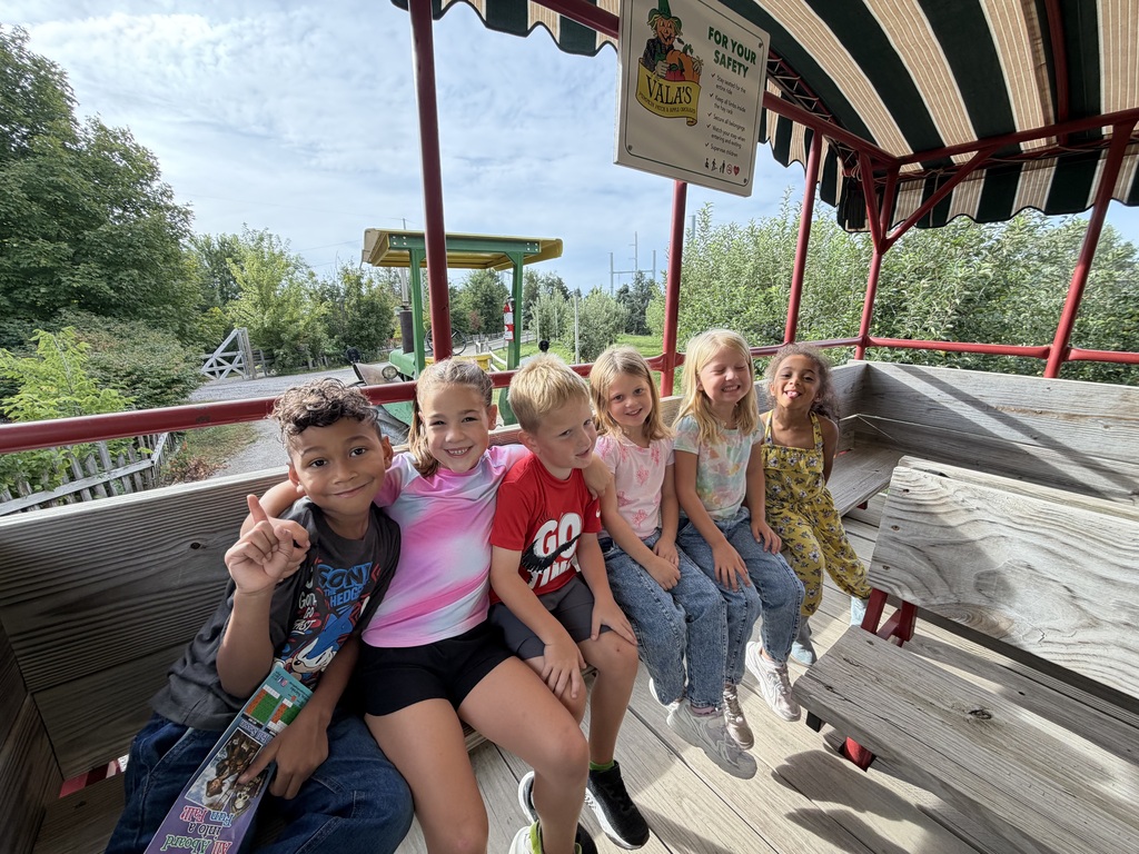 6 students are sitting on a hayrack ride to see the pumpkin patch