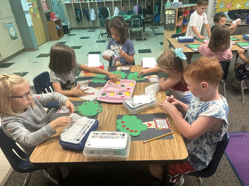 Five students are working on a fingerprint apple tree craft.