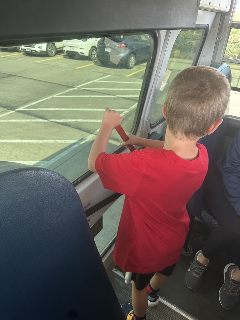A student is practicing opening up the back door of a school bus from the inside.