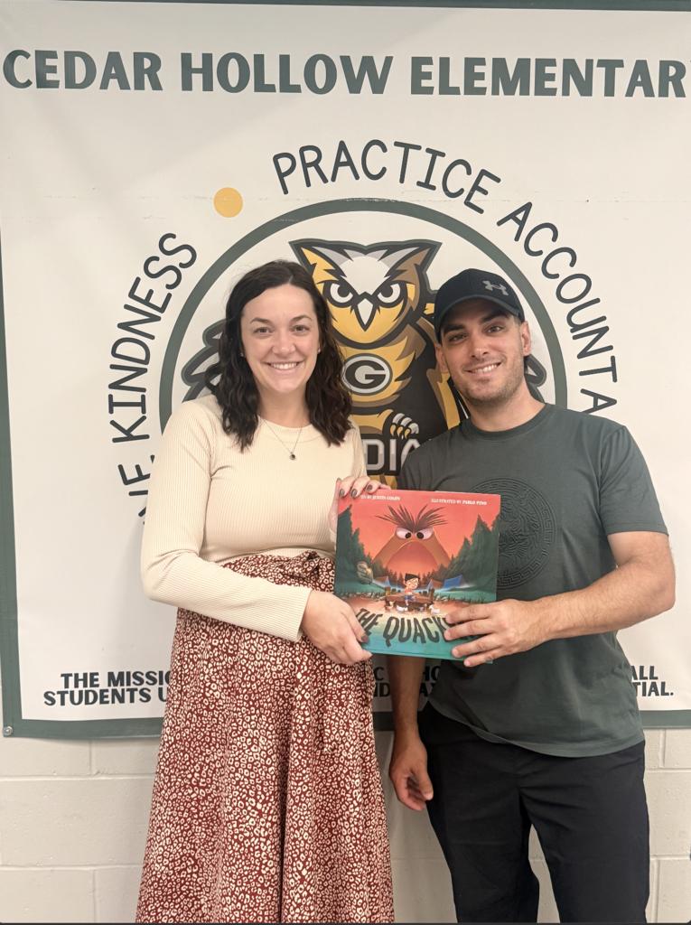 Mrs. Vacanti and Justin Colón pose for a picture with a signed copy of The Quacken.