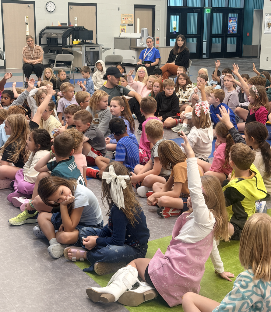 Justin sits with 2nd and 3rd grade students as they answer questions about bees!