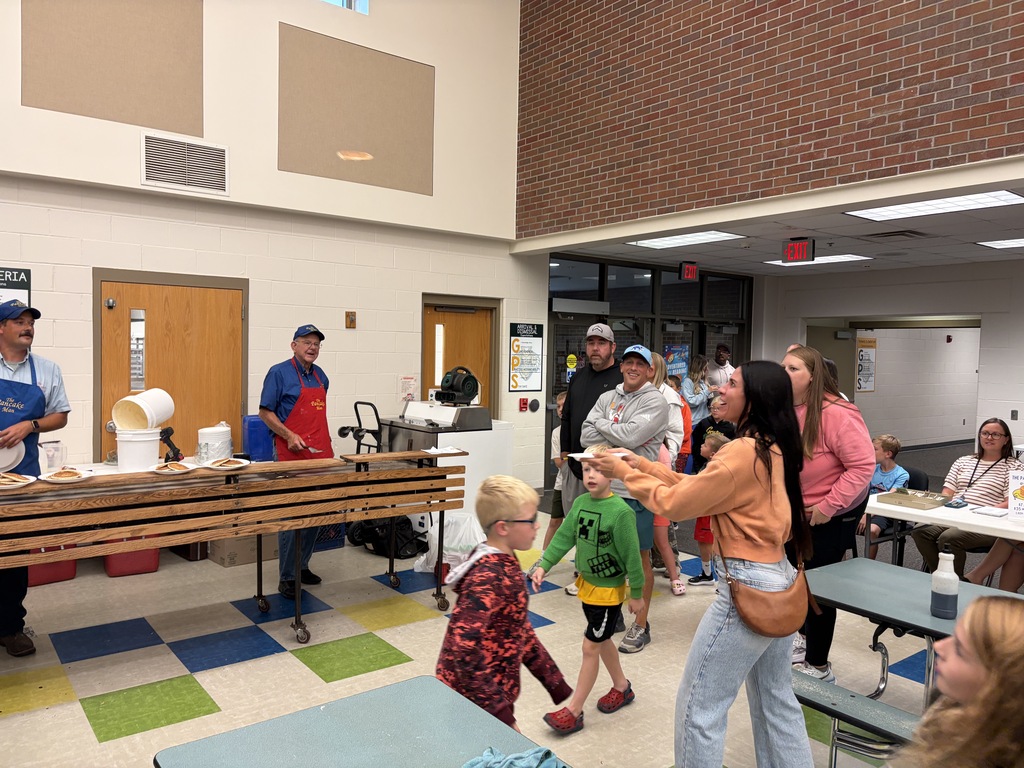 TES families in line waiting for pancakes in the cafeteria.