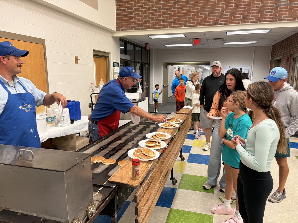 TES families in line waiting for pancakes in the cafeteria.
