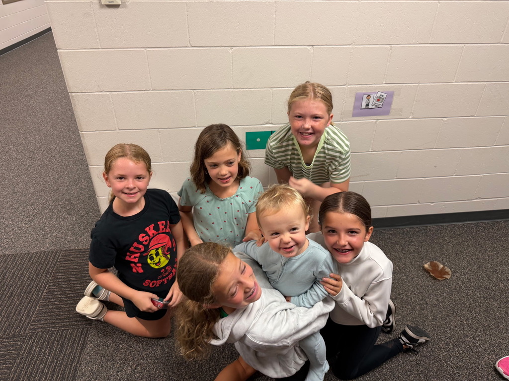 Students sitting in the hallway eating muffins and smiling. 