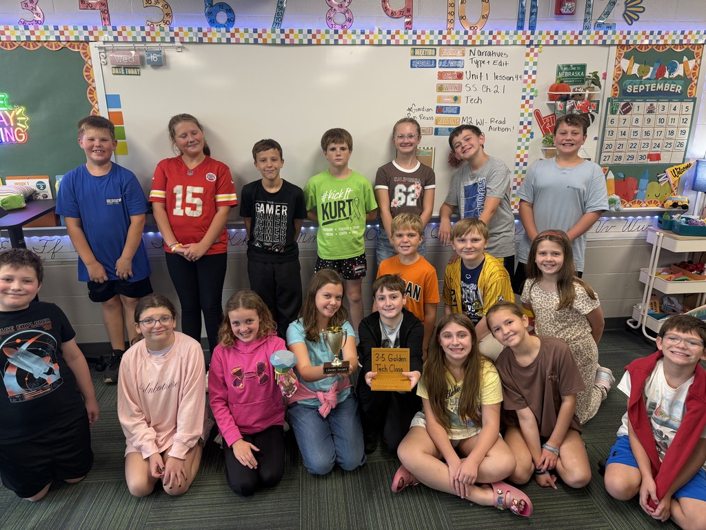 A whole class gathering together in their classroom to proudly showcase their class awards.