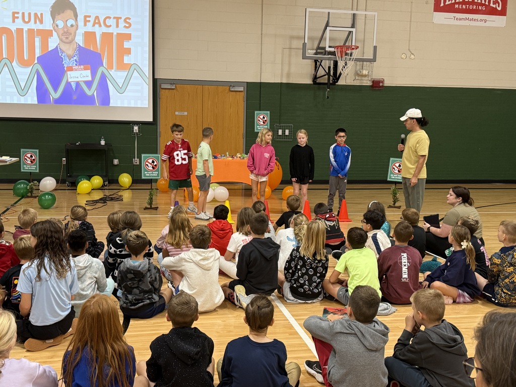A group of students standing on stage participating in an interactive school assembly.