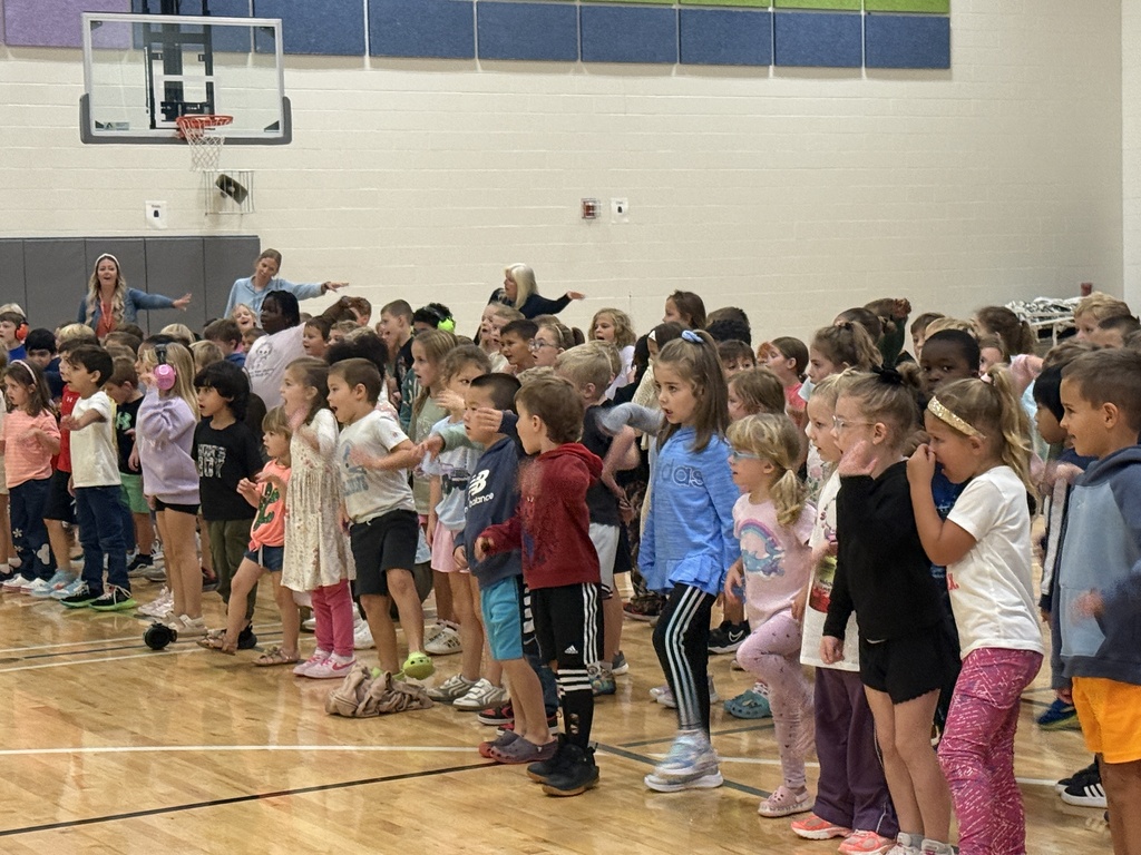 Kindergarten and first grade students are standing and shaking out a leg.