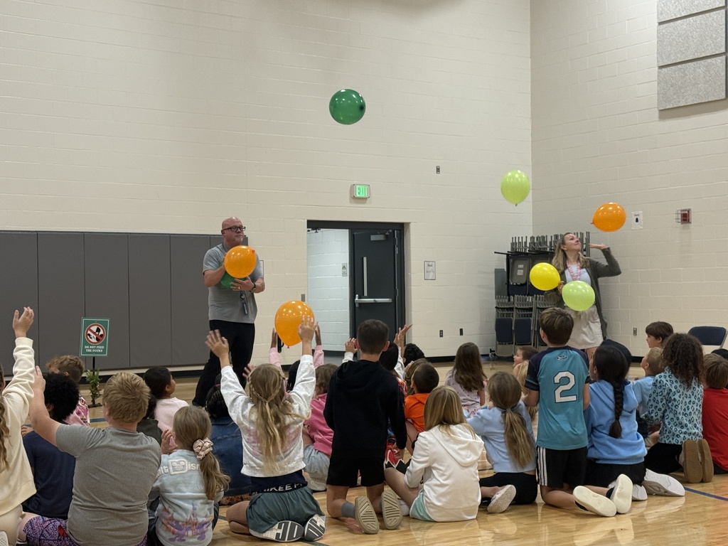 Mr. G and Mrs. Peltier stand in front of the students tossing balloons.