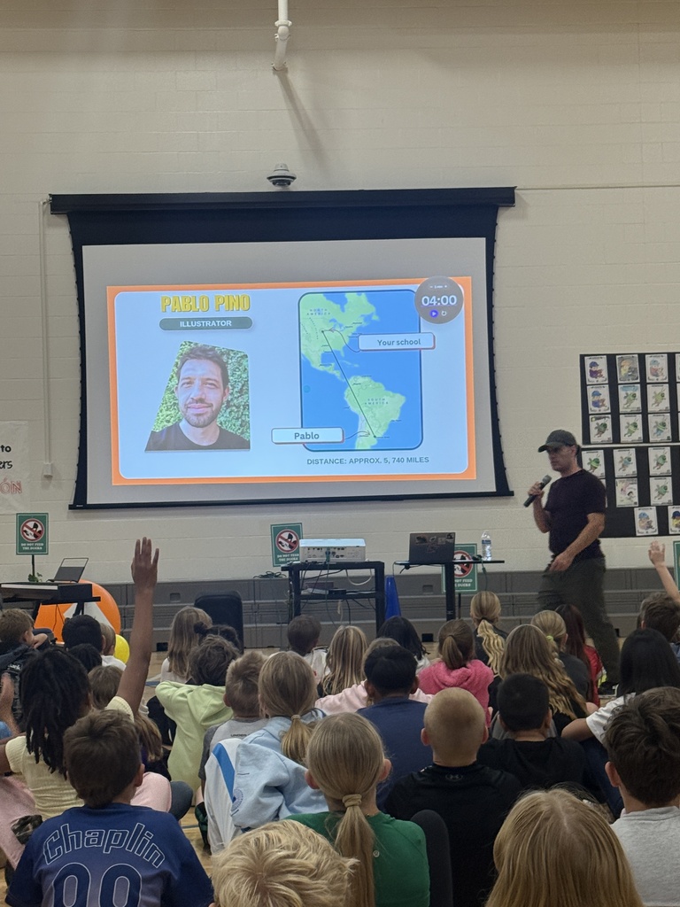 Justin stands next to a screen that shows his illustrator Pablo living in South America while we live in Nebraska.