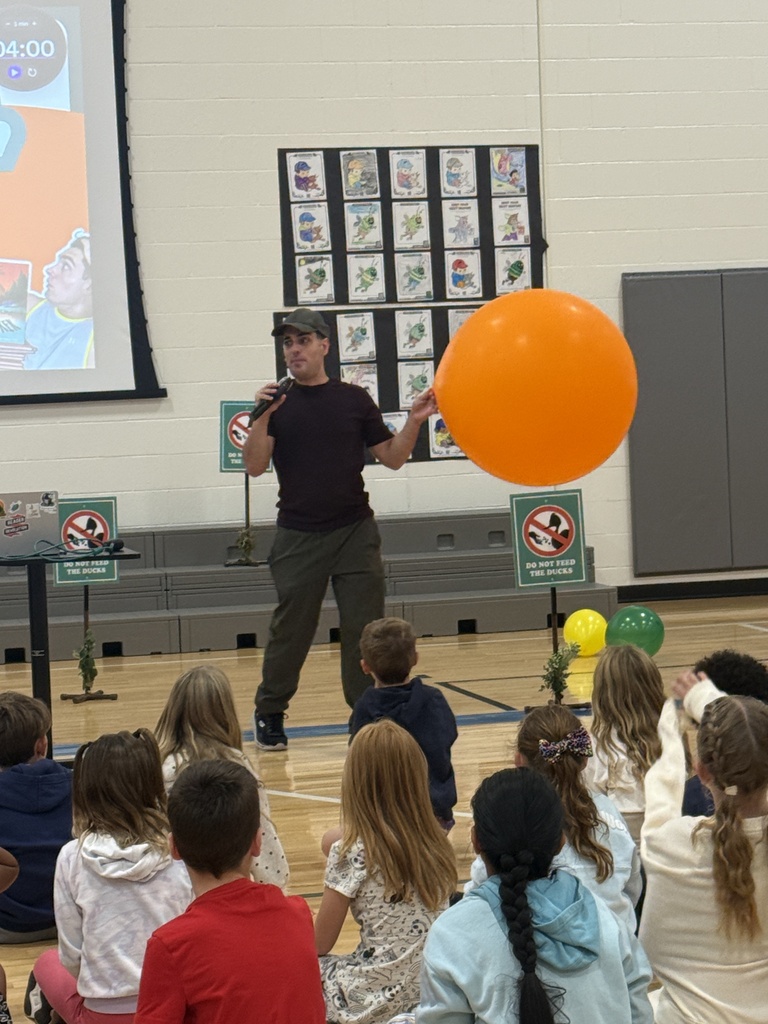Justin stands in front of the audience with an oversized orange balloon.