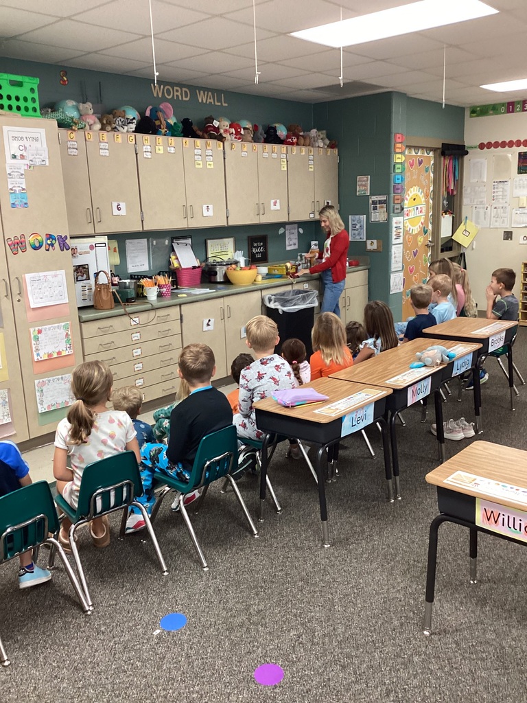 First grade students watching how to peel an apple. 