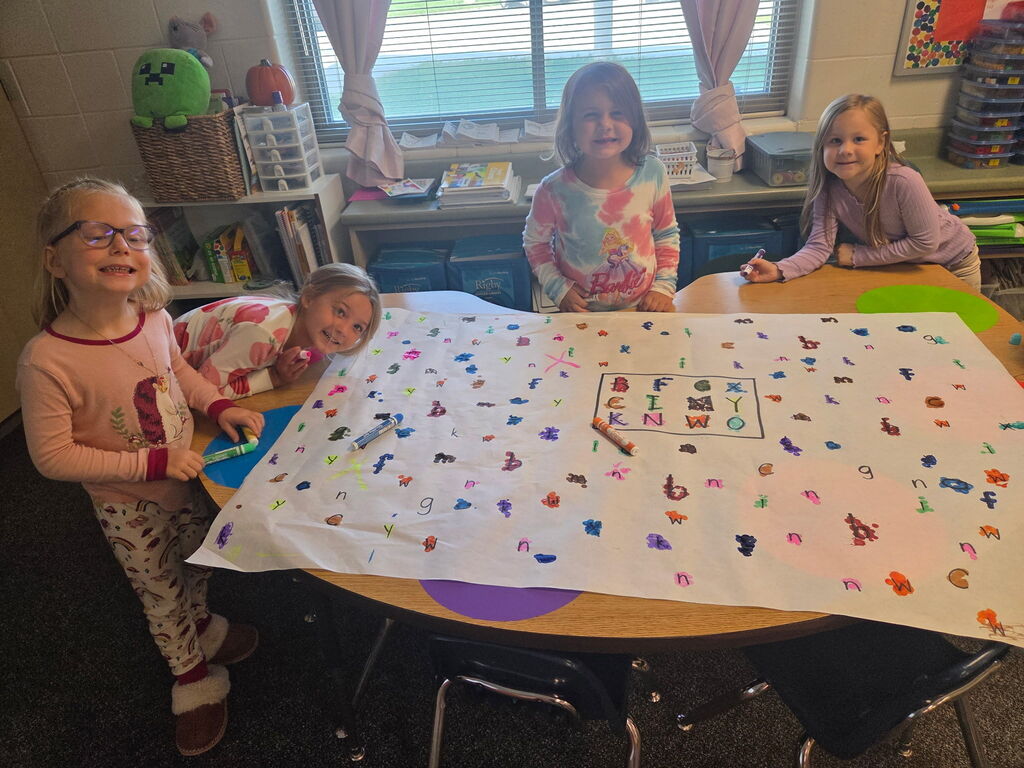 4 students are matching letters at a table.