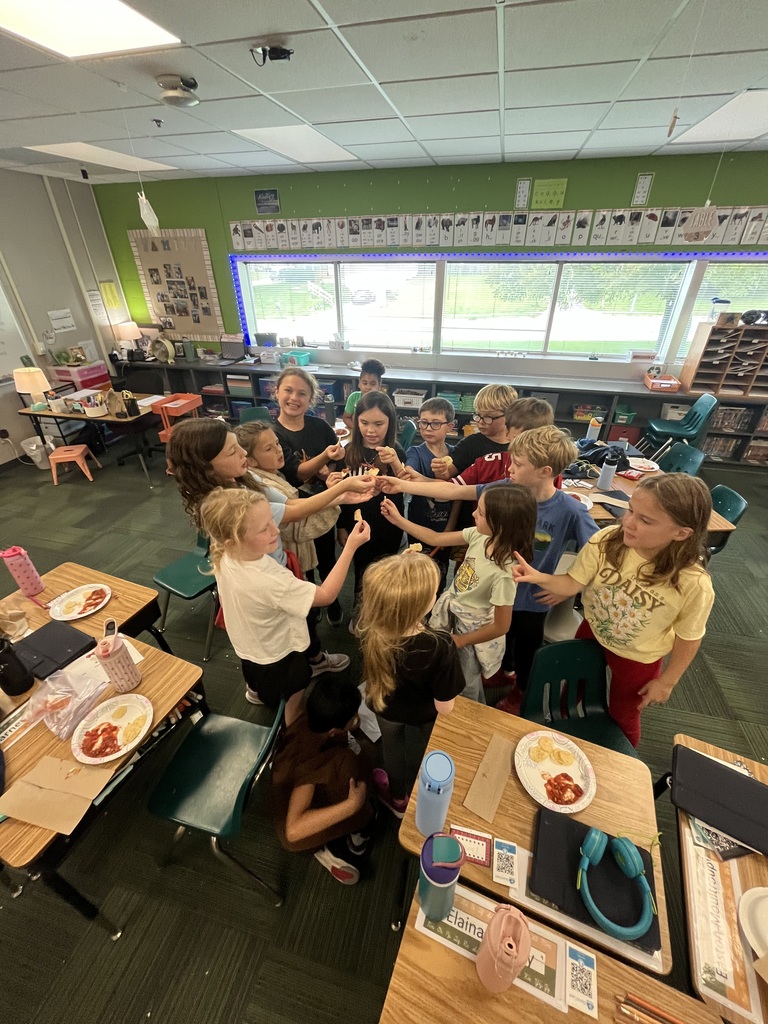 A group of students standing together in a circle holding out their chips for a group toast.
