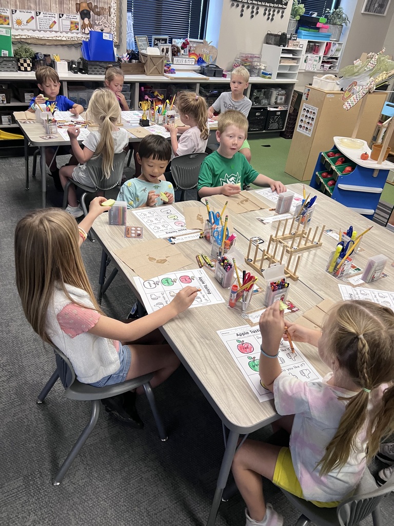 students apple tasting in class. in front of them they have an apple tasting sheet to show if they liked or disliked the apple