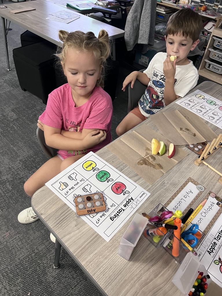 students apple tasting in class. in front of them they have an apple tasting sheet to show if they liked or disliked the apple