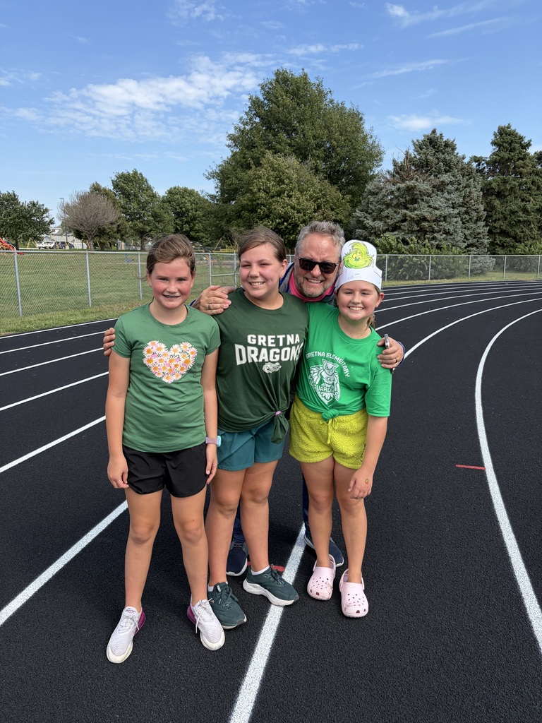A teacher posing for a picture with three students on the school running track.