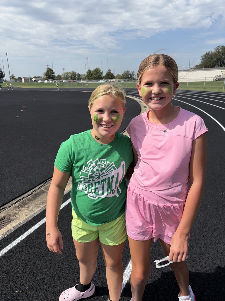 Two smiling girls with green face paint posing together on the track.