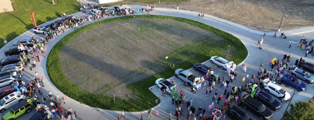 aerial view of a bus loop with cars parked and kids trick or treating