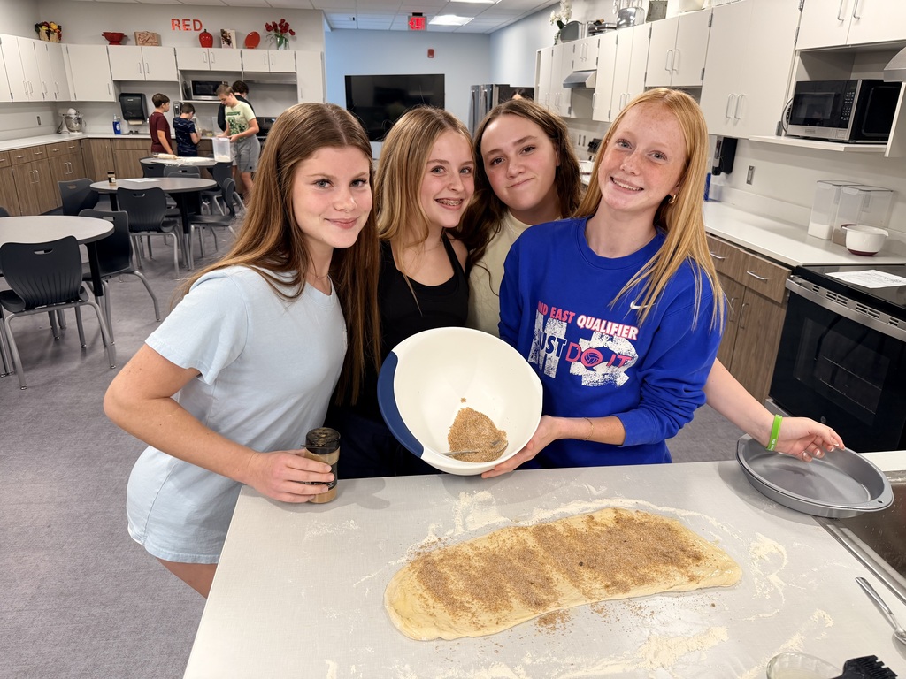 A group of four female students are showing off dough and their cinnamon topping. 