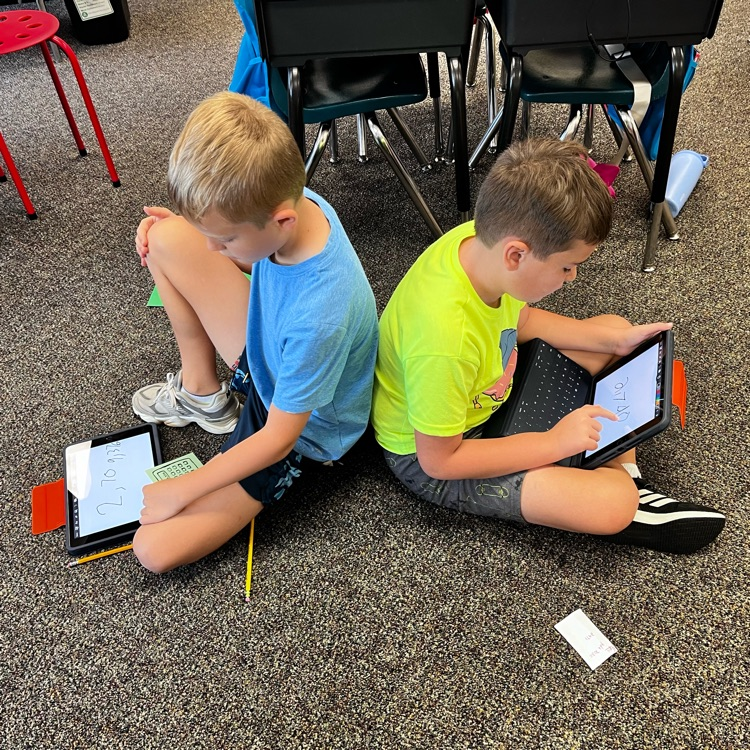 boys sitting back to back working in math