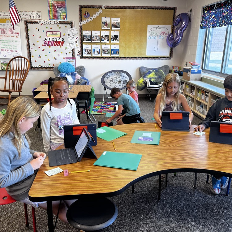 kids practicing math at a teacher table