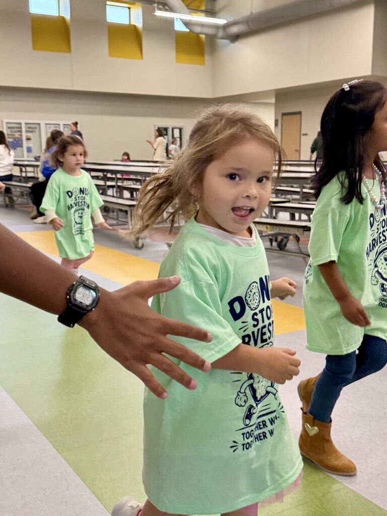 student running at the harvesst run while smiling at the camera
