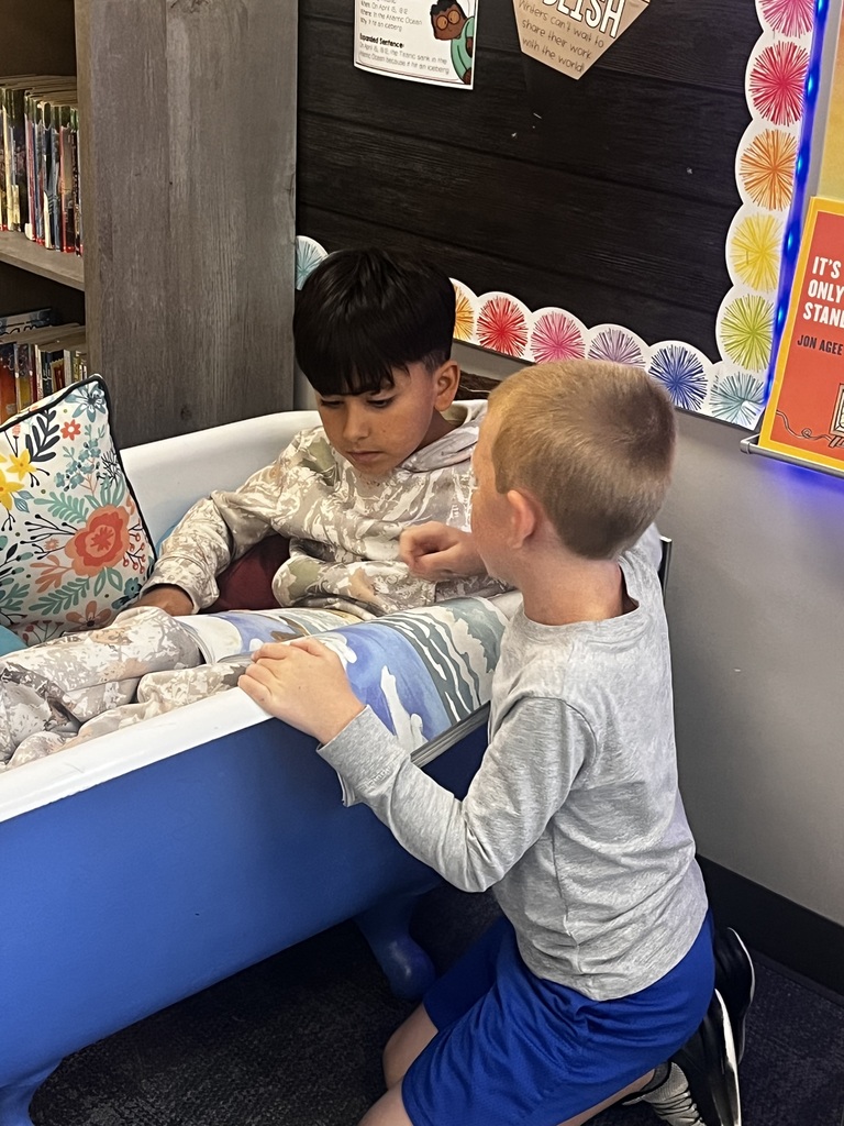 a boy in flexible seating and a boy sitting on the floor reading a story together
