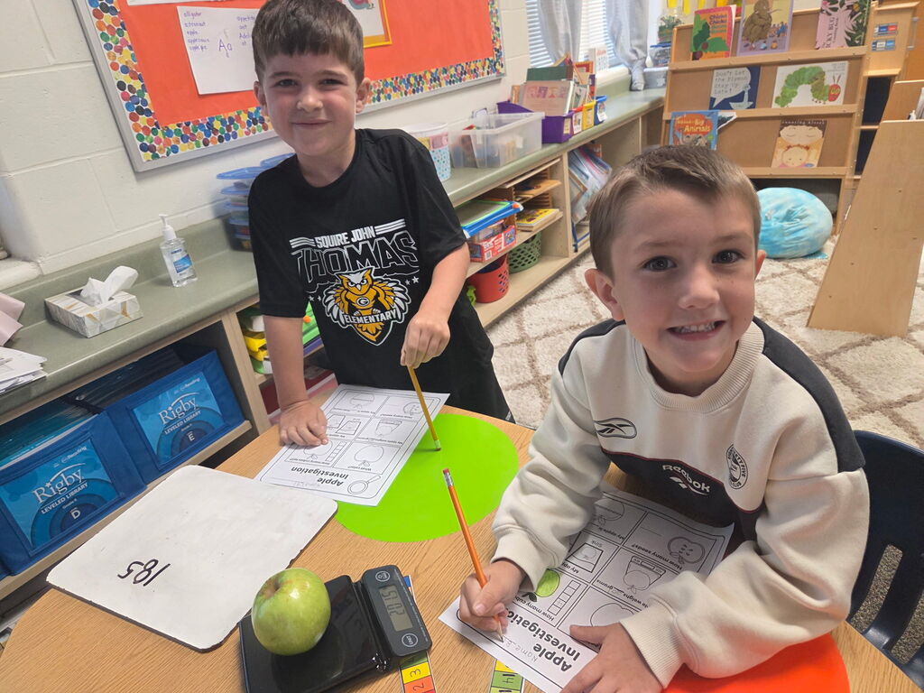 Two students work on apple explorations at their table.