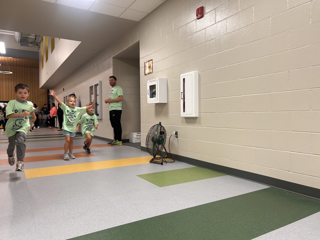 students are running in the hallway at the fun run inside harvest hills elementary